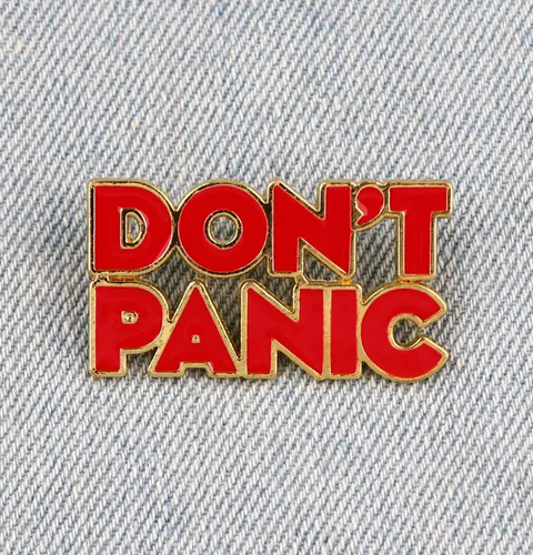 Red 'DON'T PANIC' pin on denim fabric