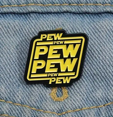 Enamel pin with 'PEW PEW' text on a denim background