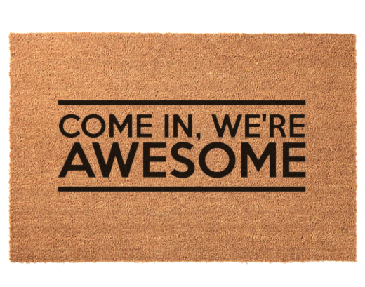 A rectangular natural coir doormat with the phrase 'COME IN, WE'RE AWESOME' printed in bold black lettering, centered on a white background.